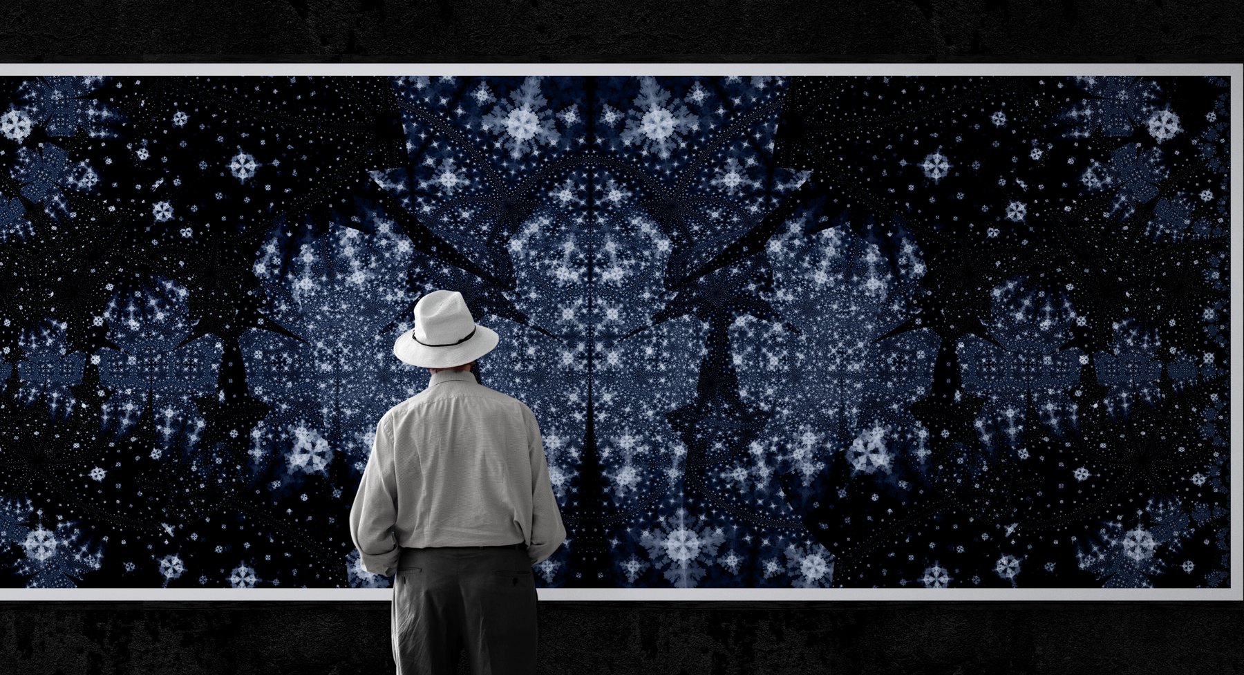 A standing figure before the illuminated installation, showing its proportion against a gallery wall.